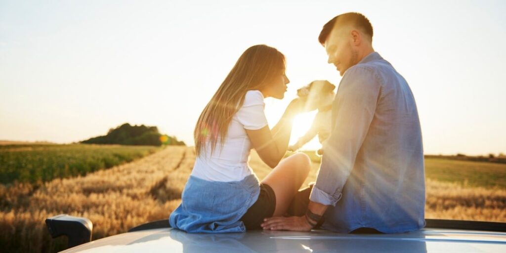 A couple and their dog at sunset.